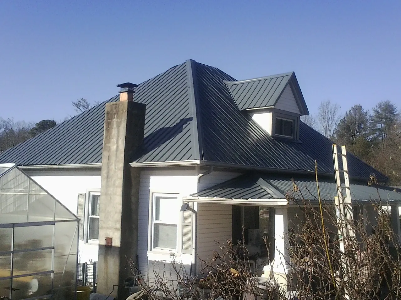 Dark blue standing seam metal roof on a white farmhouse with dormer — Slate & Tile Roof Repair by Roofing Brothers in San Carlos