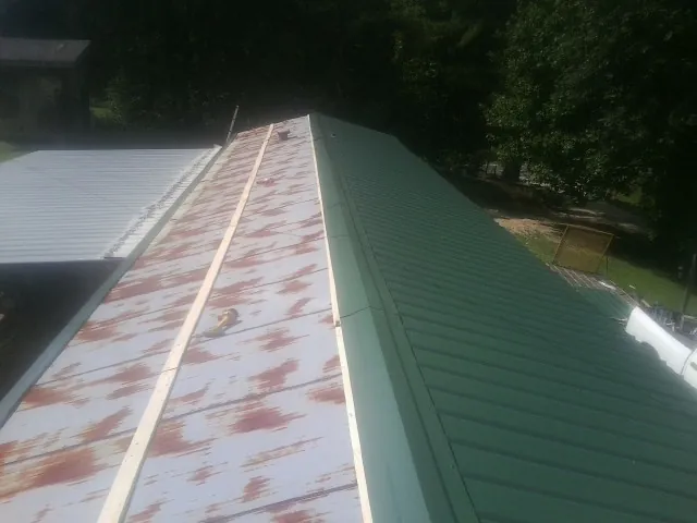 Old rusted panels beside newly installed green metal roofing — Wind Damage Roof Repair by Roofing Brothers in San Carlos