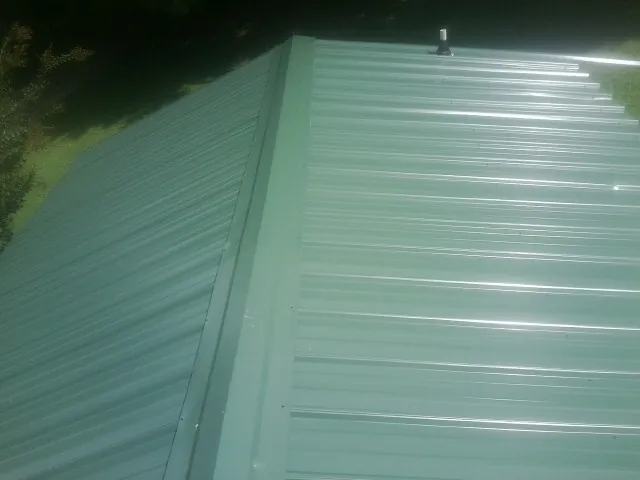 New green metal panels meeting at the ridge of a roof — Flat Roof Repair work by our crew in San Carlos