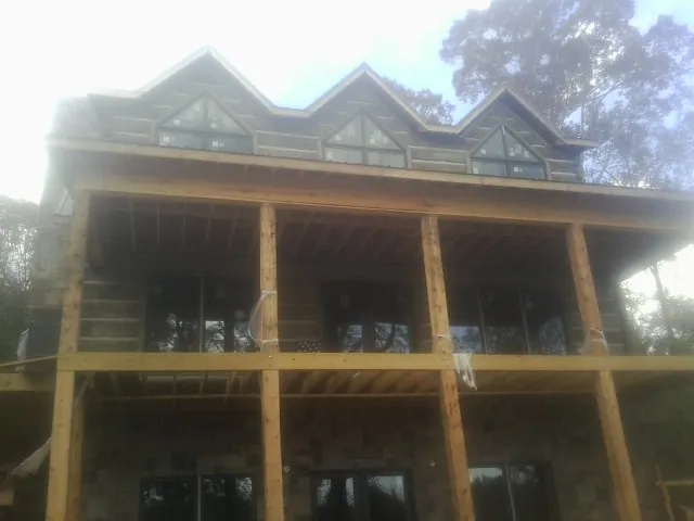 Dormers and porch framing on a large log home under construction — Roof Coating work by our crew in San Carlos