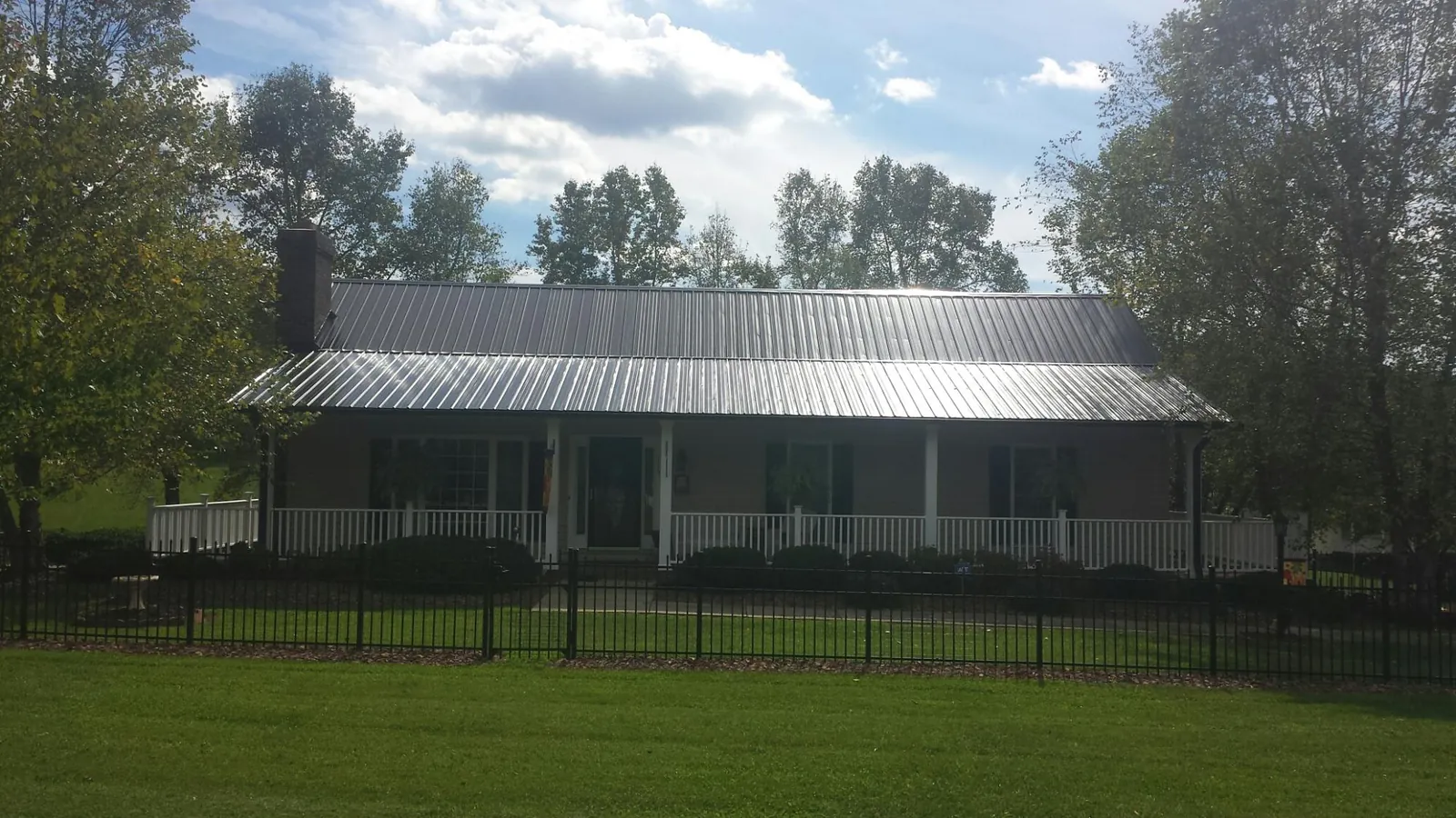Gray metal roof on a brick ranch with a full width front porch — Gutter Guard Installation work by our crew in San Carlos