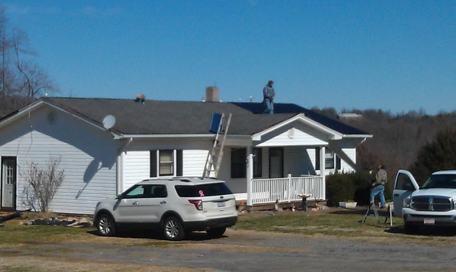 Roofers stripping shingles from a white ranch house roof in San Carlos