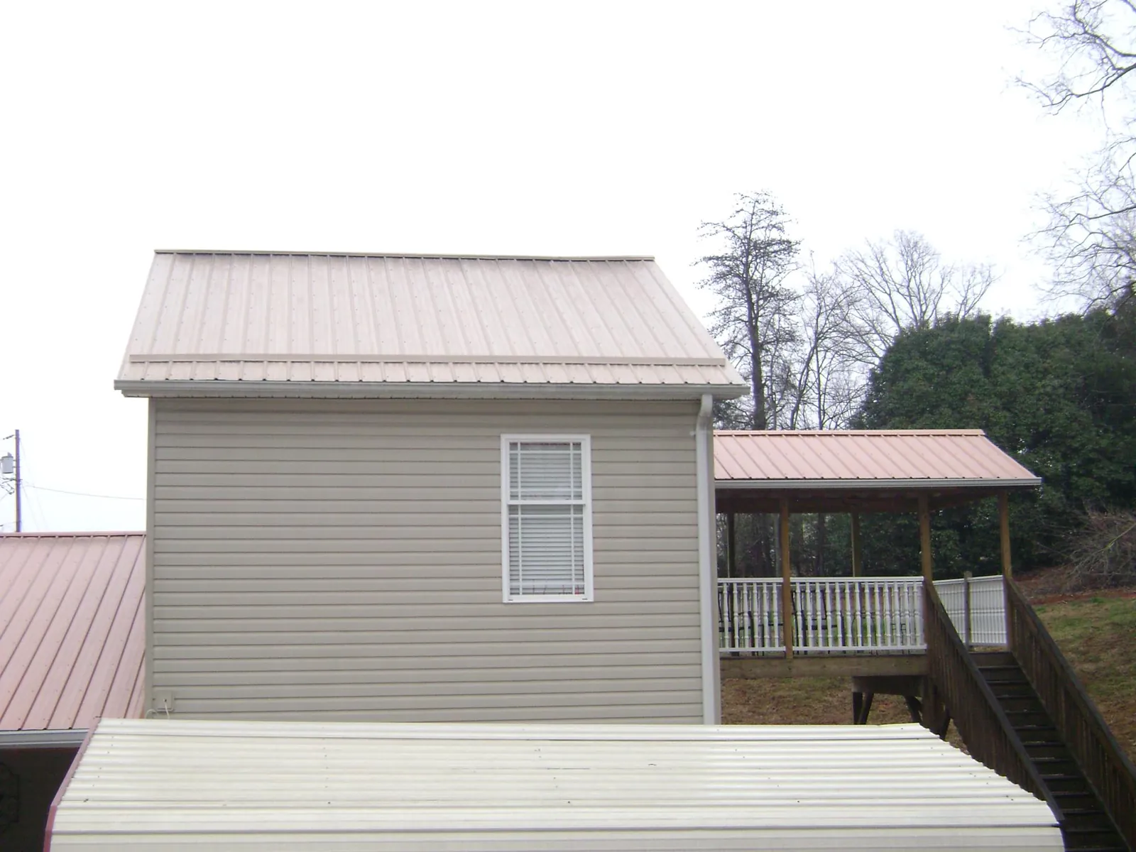 Tan metal roofs on a two story addition and attached porch, from a Roof Replacement job in San Carlos