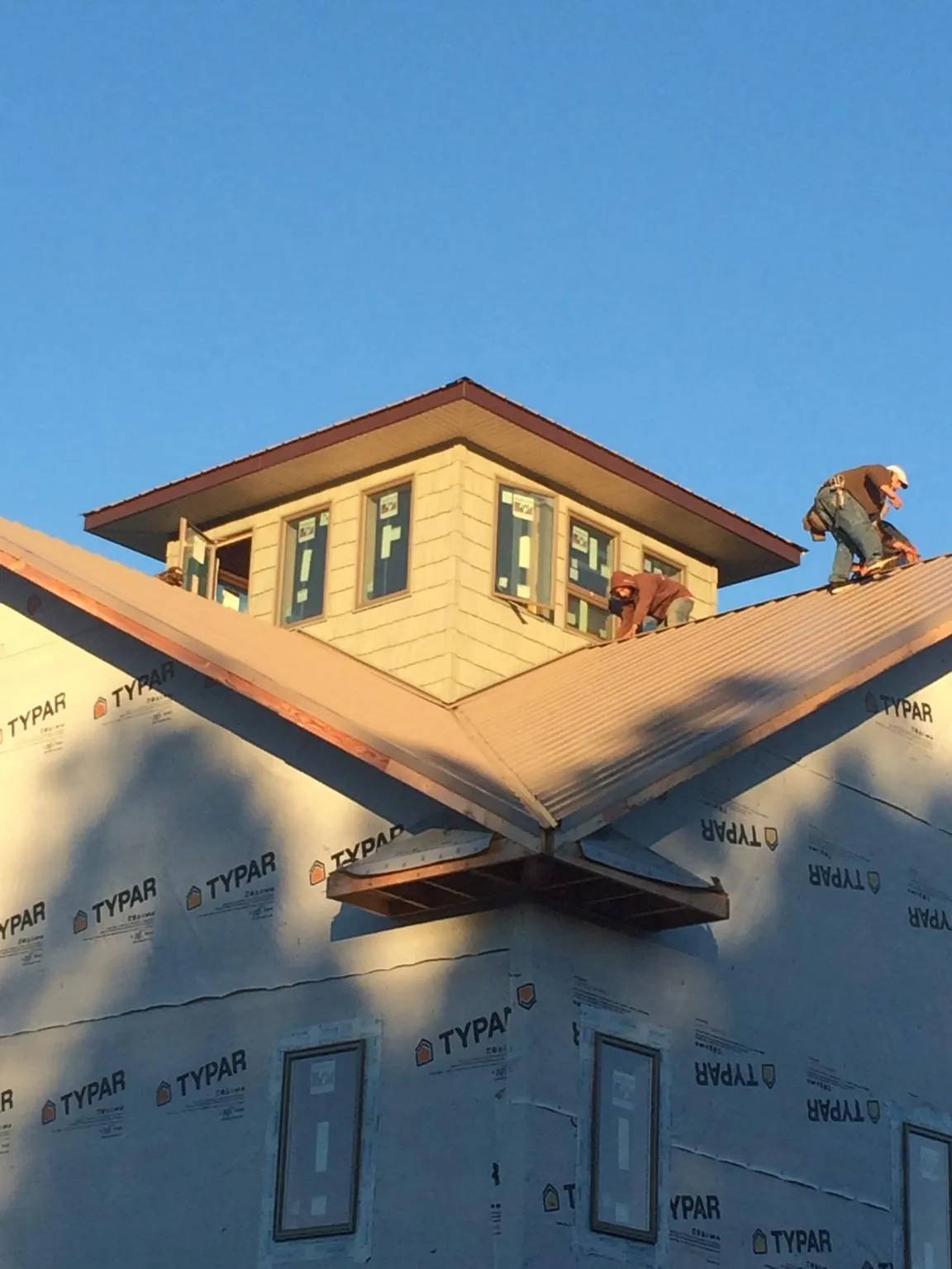Roofers working around a rooftop cupola on a new metal roof at sunset — Roof Waterproofing in San Carlos by Roofing Brothers